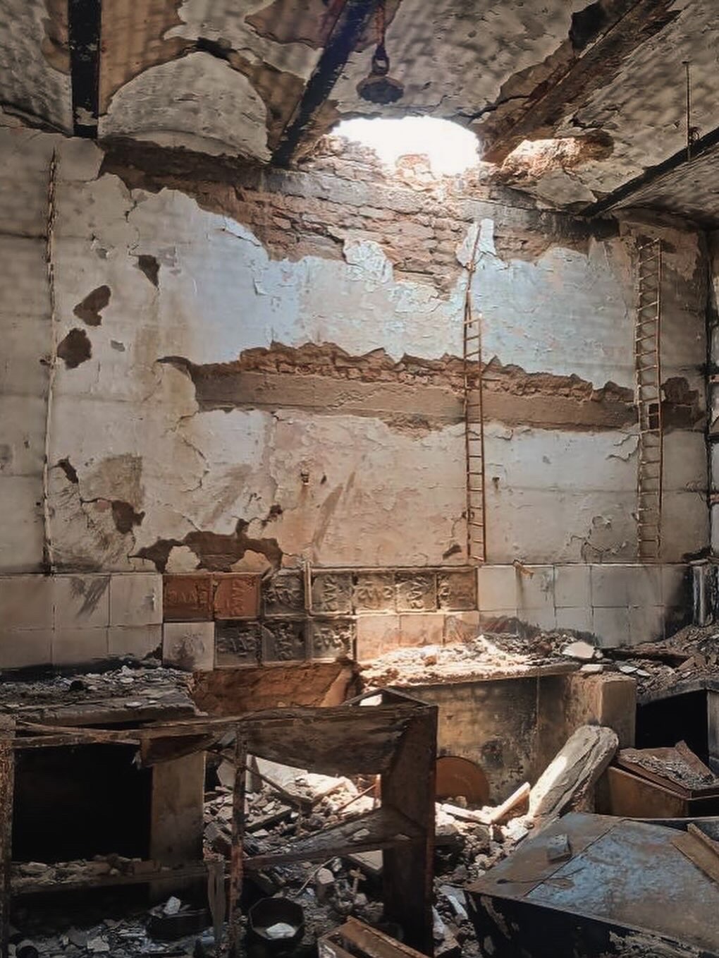 Fire and looting damage inside the shop, including a hole burned through the roof, before repair